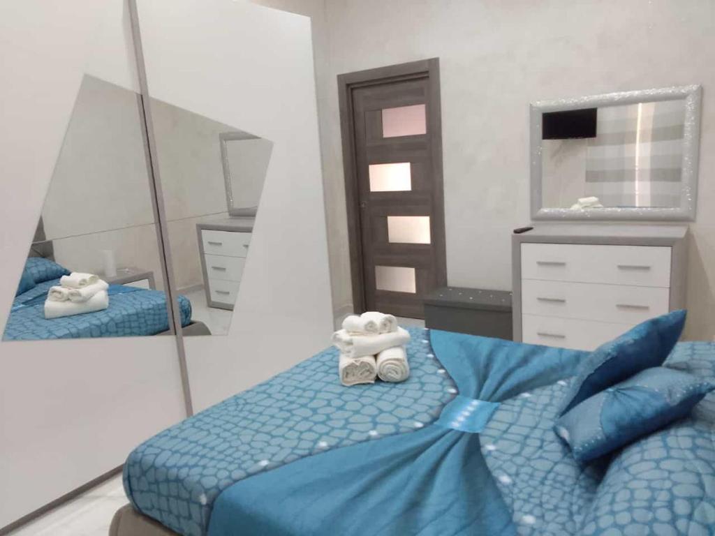 1 dormitorio con cama azul y espejo en Casa Vacanza da Nunzio, en Torre Annunziata