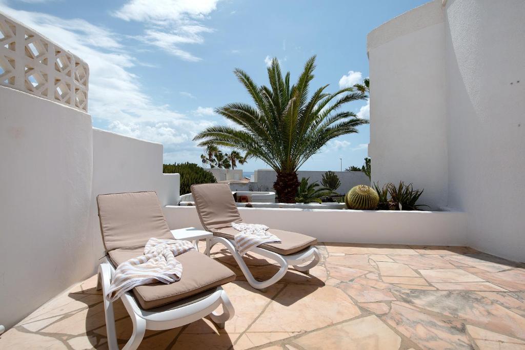 a patio with two chairs and a palm tree at Casa Campana in Costa Calma