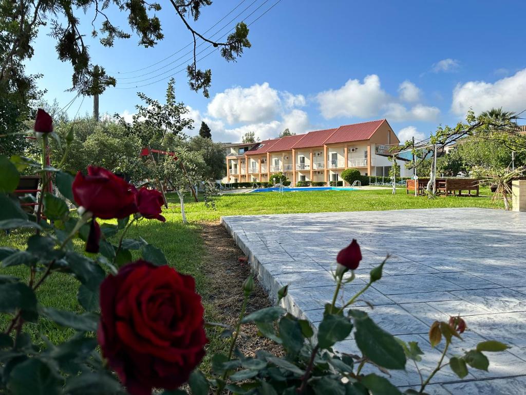 a house with red roses in front of a driveway at Aggelos Family Hotel in Moraitika