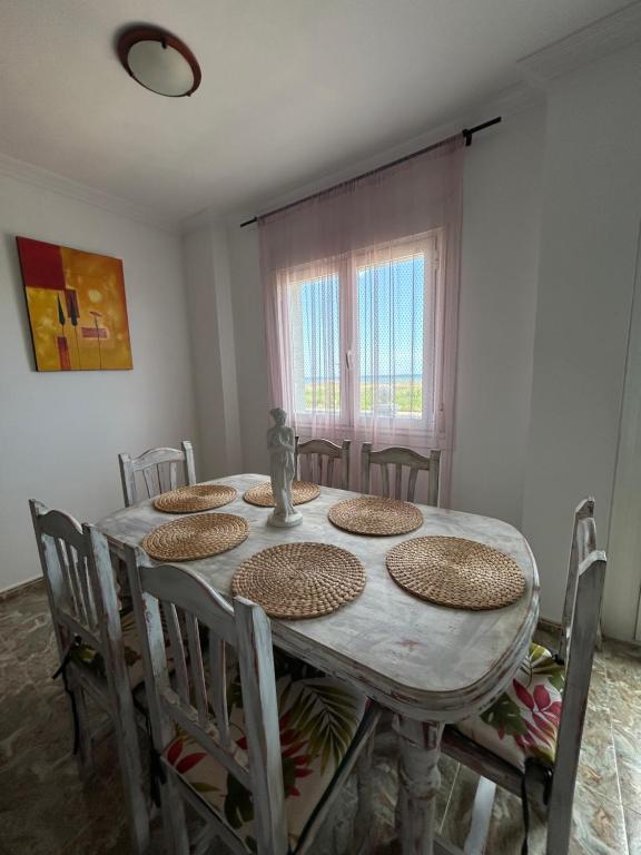 d'une salle à manger avec une table, des chaises et une fenêtre. dans l'établissement Apartamentos Mar Menor, à Los Alcázares