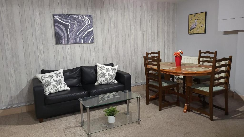 a living room with a black couch and a table at Fully Furnished 3 bedroom Appartment in Bristol