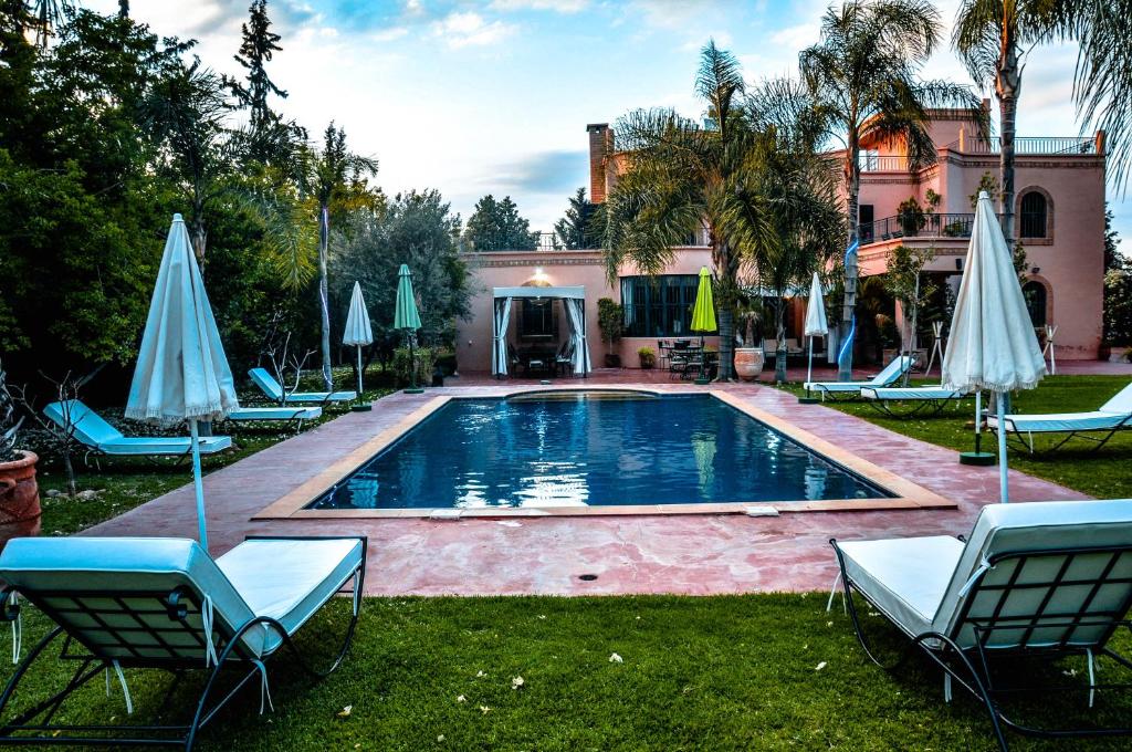 a pool with chairs and umbrellas in front of a house at Riad Dar Biona Maison D'hôtes & Spa in Aït Zat