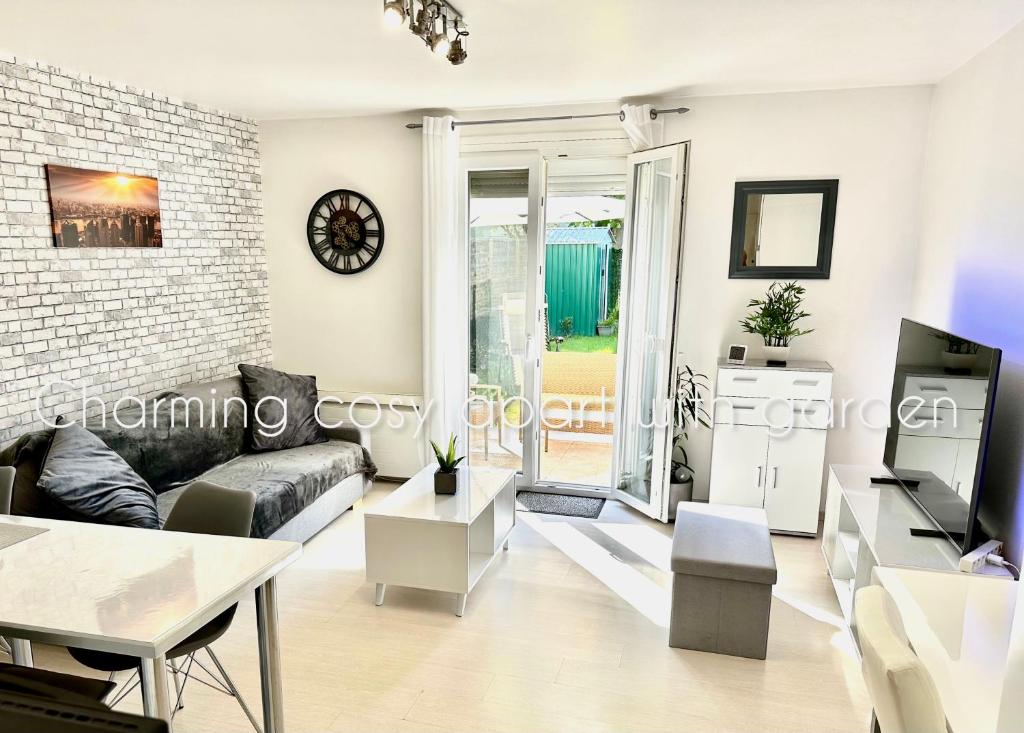 a living room with a couch and a tv at Charming cosy apart with garden free parking in Claye-Souilly