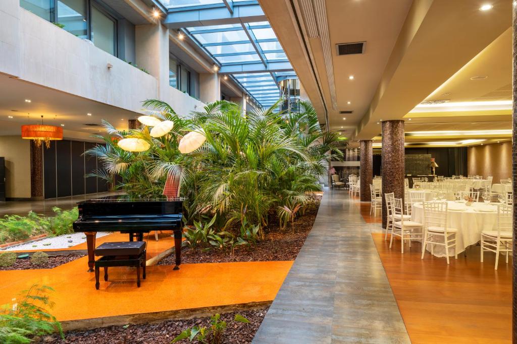 un pianoforte a coda in un ristorante con tavoli e sedie di Iberik Santo Domingo Plaza Hotel a Oviedo