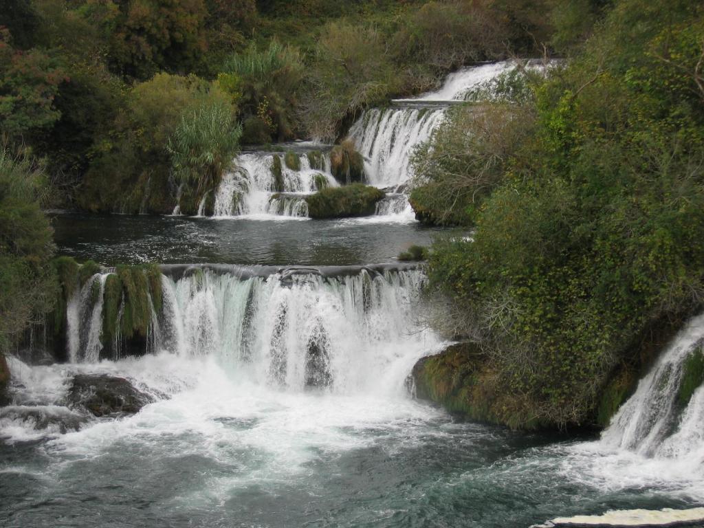 un groupe de cascades dans une rivière arborée dans l'établissement Guesthouse Juric, à Skradin