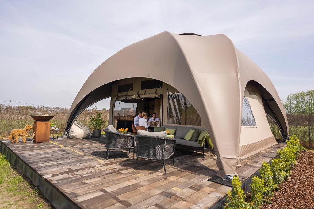 una tenda su una terrazza in legno con 2 persone di Vakantie plezier Vlaanderen a Zedelgem
