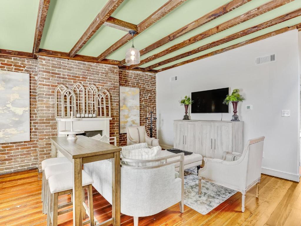 een woonkamer met een bakstenen muur en een tafel en stoelen bij Gordon Inn Tree Top in Savannah