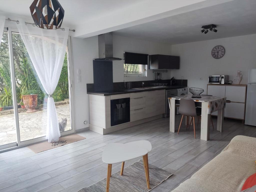 a kitchen and living room with a table and chairs at Charmant studio à Castillon du Gard in Castillon-du-Gard