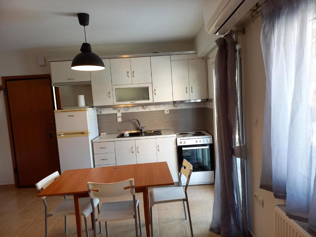 a kitchen with a wooden table and white cabinets at dimis apartment in Nea Michaniona