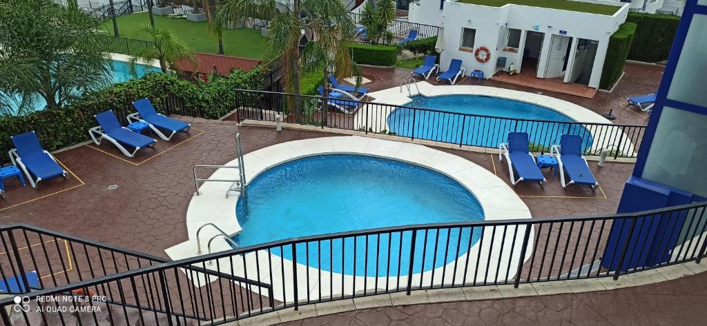 basen z niebieskimi leżakami i basenem w obiekcie 2 Paradise of Benalmádena Residencial Los Patos II a 300 metros de la playa y supermercados, wifi gratis, vistas a la montaña w mieście Benalmádena