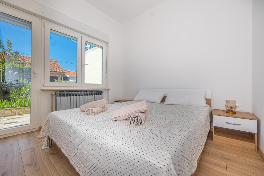 biała sypialnia z łóżkiem i oknem w obiekcie Happy Holiday w mieście Dramalj
