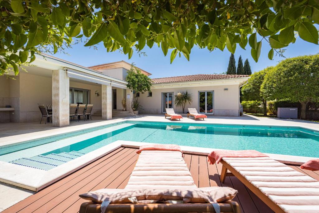 una piscina con terraza y una casa en Luxurious Volme199 (4* Home) en Banjole