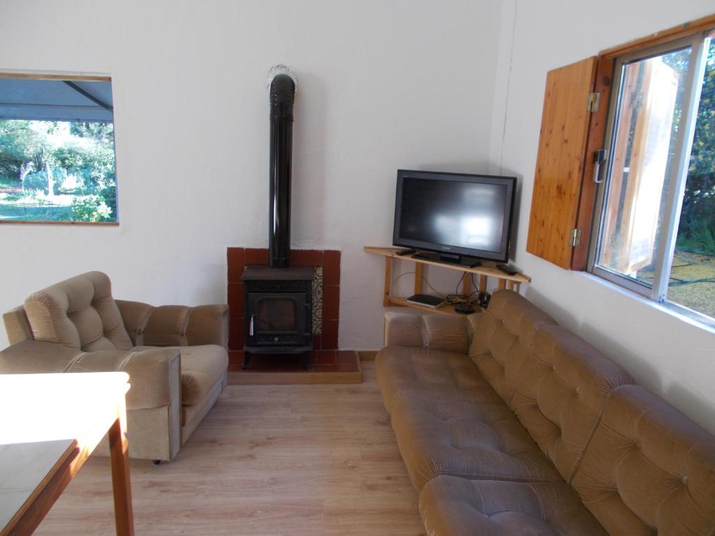 ein Wohnzimmer mit einem Sofa, einem TV und einem Herd in der Unterkunft Casa Fonte in Santo Estêvão