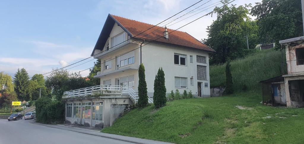 una casa blanca en una colina al lado de una calle en Apartman Jurak en Travnik