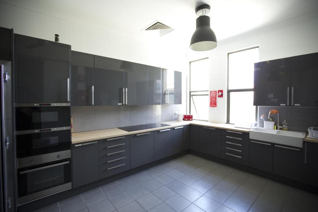 a kitchen with black cabinets and a large window at EBS Sydney Hostel in Sydney