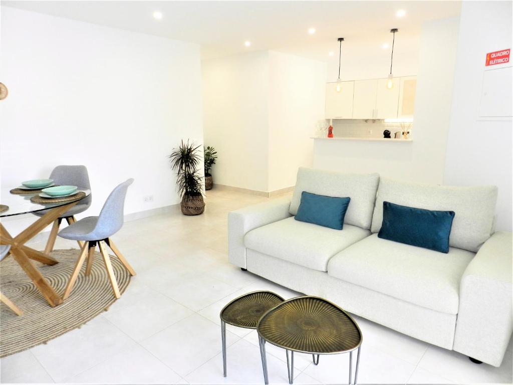 een woonkamer met een witte bank en een tafel bij Carvoeiro Boutique Apartment in Carvoeiro