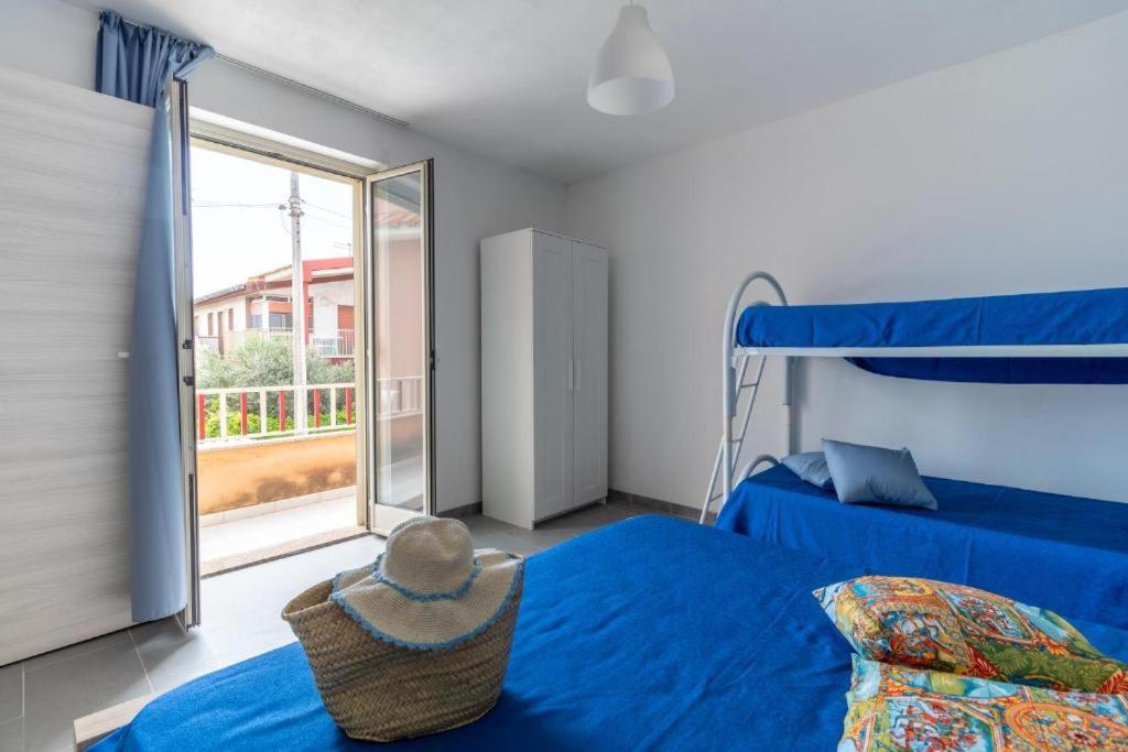 - une chambre avec un lit bleu et une fenêtre dans l'établissement Oasi del mare, à Granelli