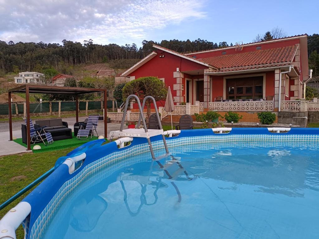 a swimming pool with a slide in front of a house at Casa/chalet en Sanxenxo 3hab. in Sanxenxo