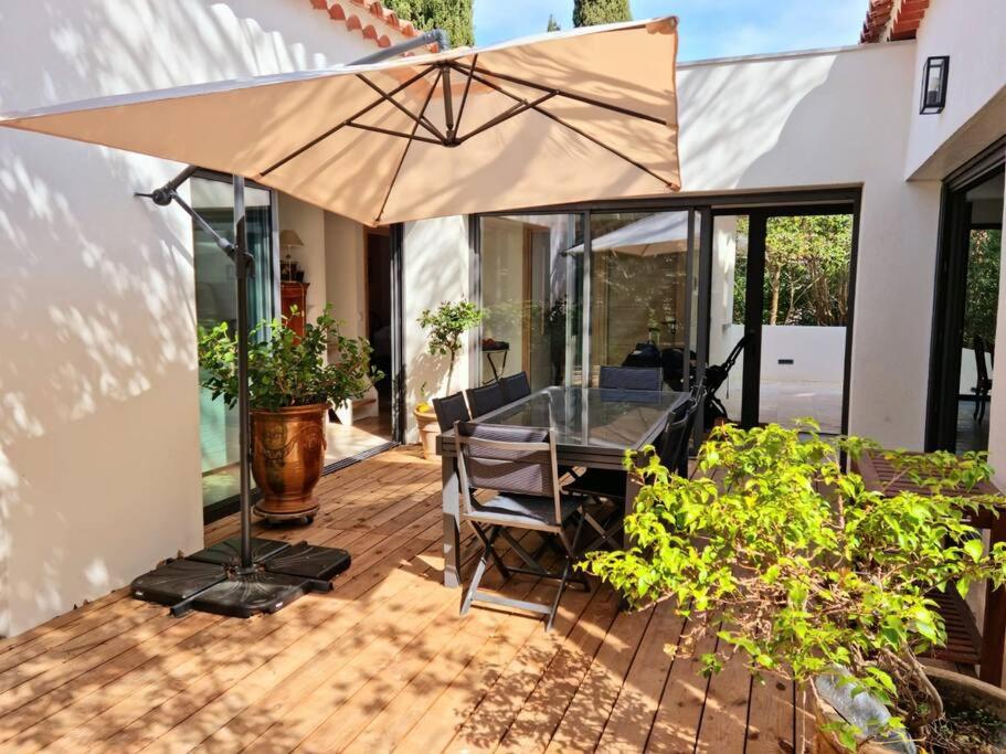 eine Terrasse mit einem Tisch und einem Sonnenschirm in der Unterkunft Spacieuse villa, environs 10 min à pied des plages in La Garde