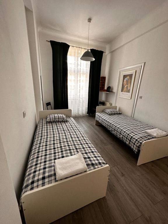 two beds are in a room with a window at Centrum ARTLwowska in Warsaw