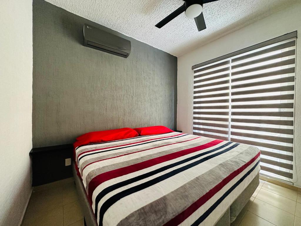 Un dormitorio con una cama con una almohada roja. en Depa Xcalacoco, Playa Del Carmen en Playa del Carmen