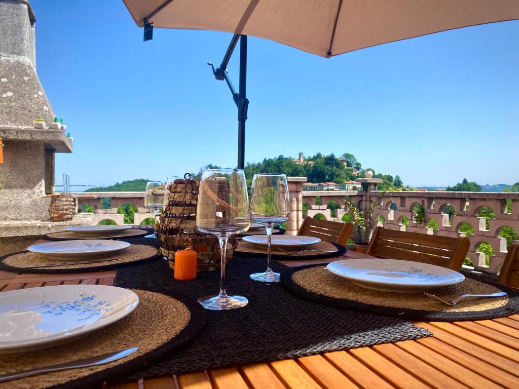 uma mesa com pratos e copos de vinho num deque em CASA BARBERA Terrazza sul Monferrato em Serralunga di Crea