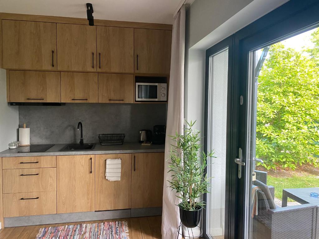 a kitchen with wooden cabinets and a sliding glass door at Dom Wypoczynkowy Zacisze- klimatyczny domek z kominkiem in Stegna