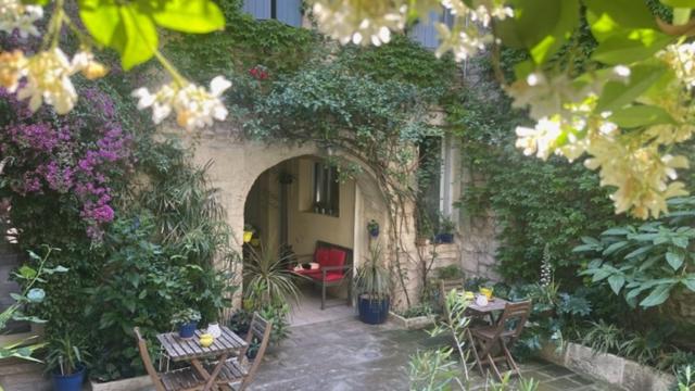 un patio al aire libre con mesas, sillas y plantas en LE ROUGET, en Beaucaire