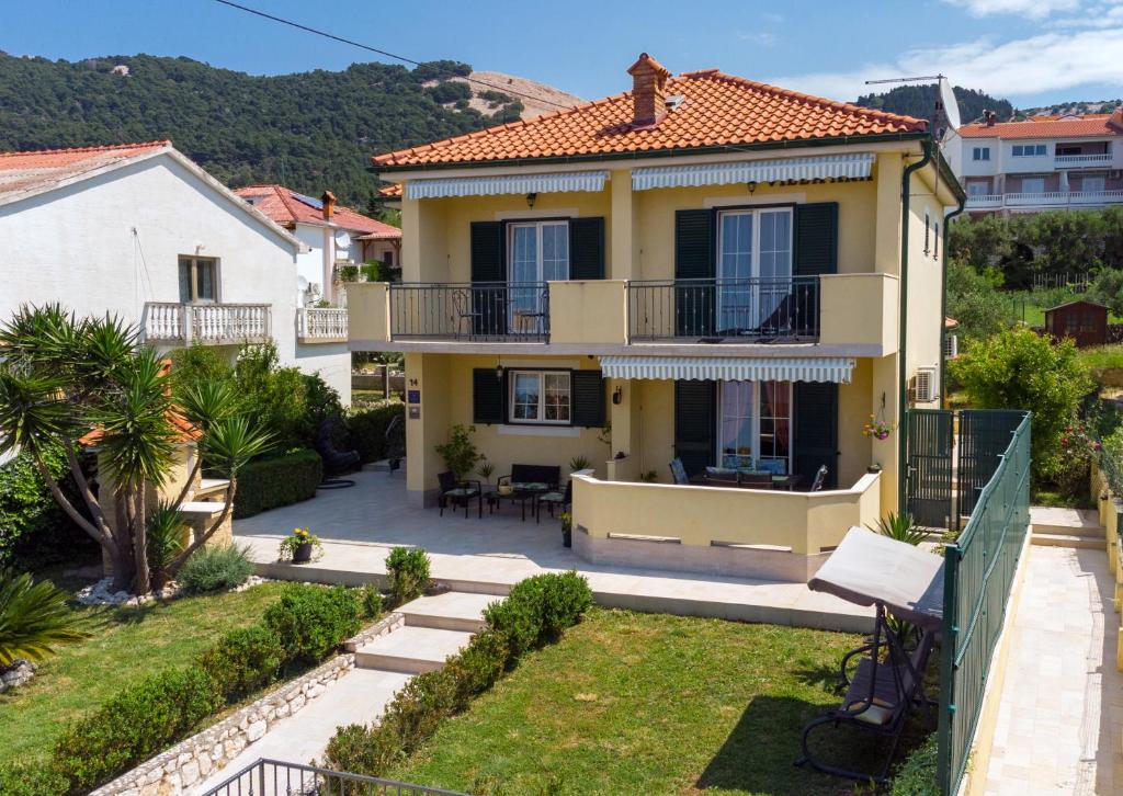 ein Haus mit einem Balkon und einem Hof in der Unterkunft Villa Ana in Rab