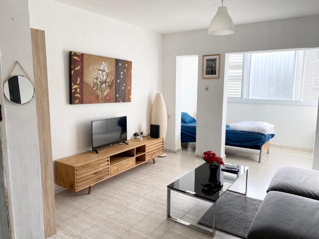 uma sala de estar com uma televisão e um sofá em Прекрасная квартира на берегу Средиземного моря em Qiryat H̱ayyim