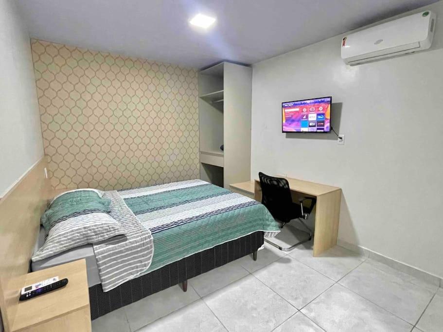 Schlafzimmer mit einem Bett, einem Schreibtisch und einem TV in der Unterkunft Apartamento Studio Centro in Macapá