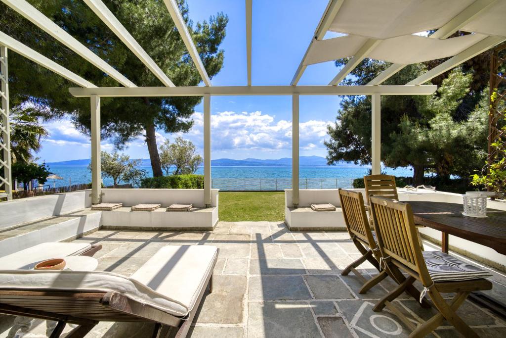 un patio con tavolo, sedie e vista sull'oceano di MARVELOUS BEACH HOUSE a Eretria