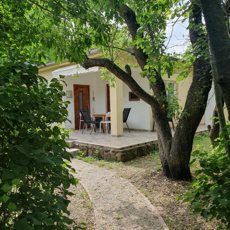 a house with a table and chairs on a porch at Budatava nyaraló in Balatonalmádi