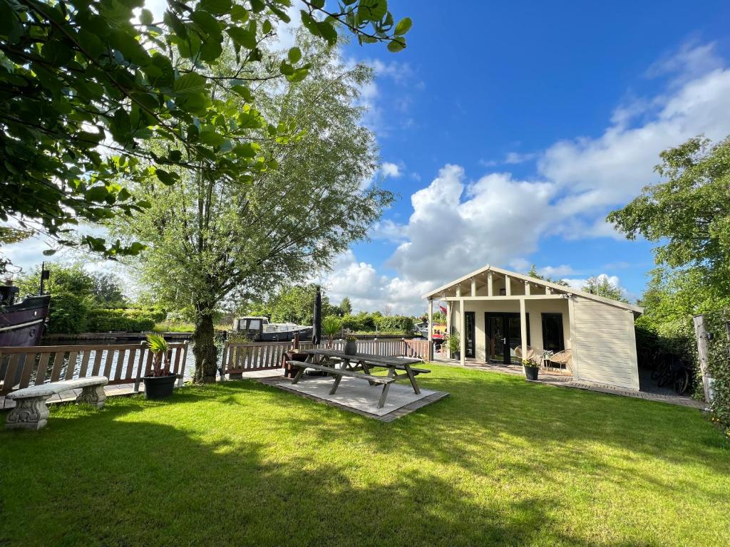 a picnic table and bench in a yard with a building at NEW - Private Cabin - on a lake near Amsterdam in Vinkeveen