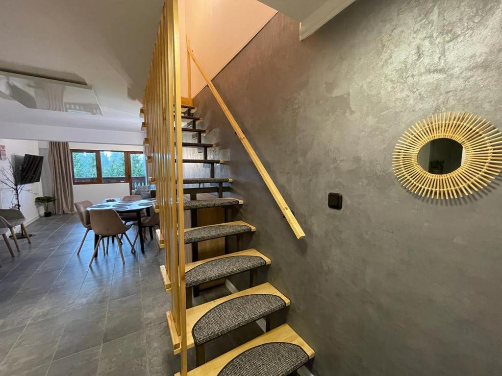 a staircase in a room with a table and a mirror at Harmony Apartment Poiana Brasov in Poiana Brasov