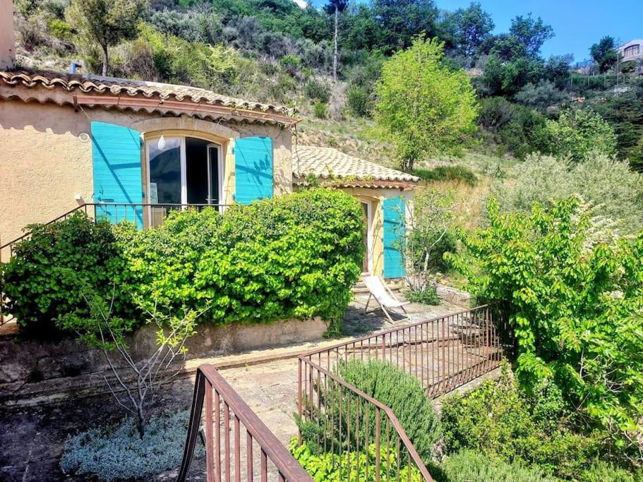 una casa con una puerta azul y algunos arbustos en La maison de Ninia, en Digne-les-Bains