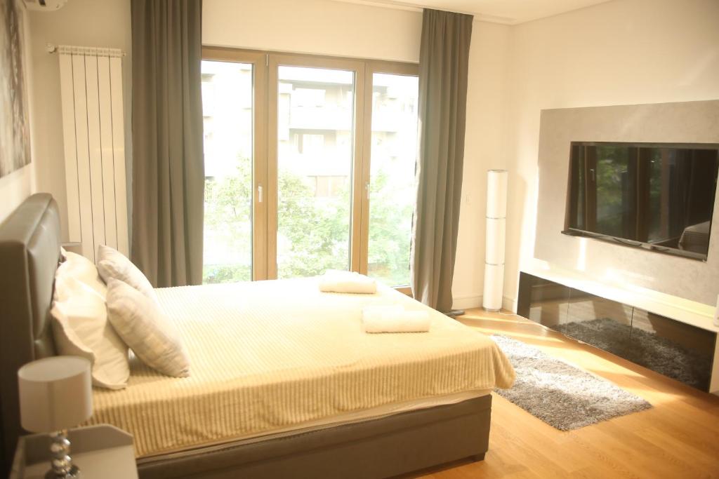 um quarto com uma cama e uma grande janela em Natalie's Condo em Belgrado
