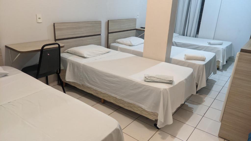 um quarto de hospital com três camas e uma secretária em PREMIER HOTEL em Marabá