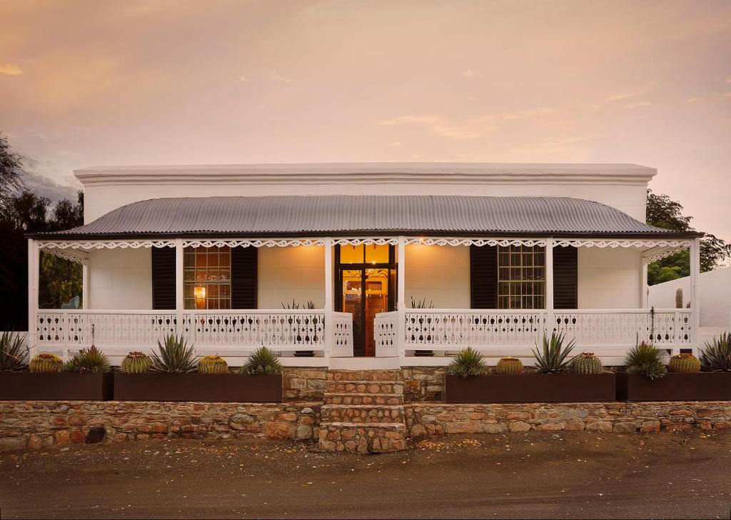 een wit huis met een veranda en een wit hek bij Mukti in Nieu-Bethesda