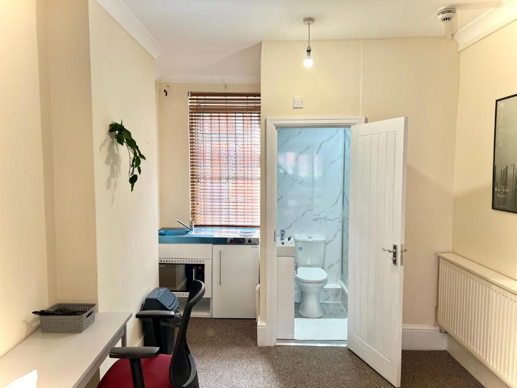 een badkamer met een toilet, een wastafel en een bureau bij Aldgate Holiday Rooms in Londen