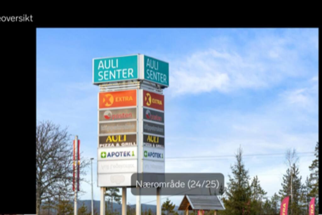 um sinal para um posto de gasolina com muitos sinais nele em 4-mannsbolig sentralt i Auli 