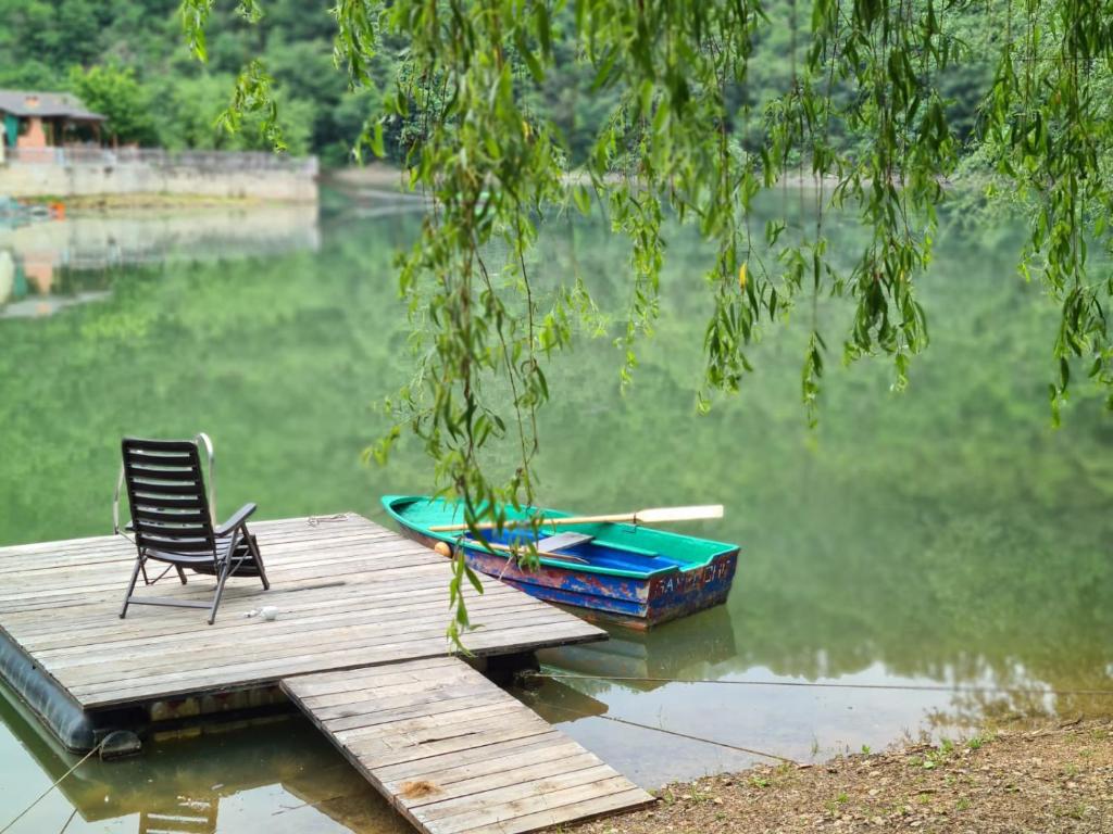 uma cadeira sentada numa doca com um barco na água em Cabana Gavroche em Moara Ungurului