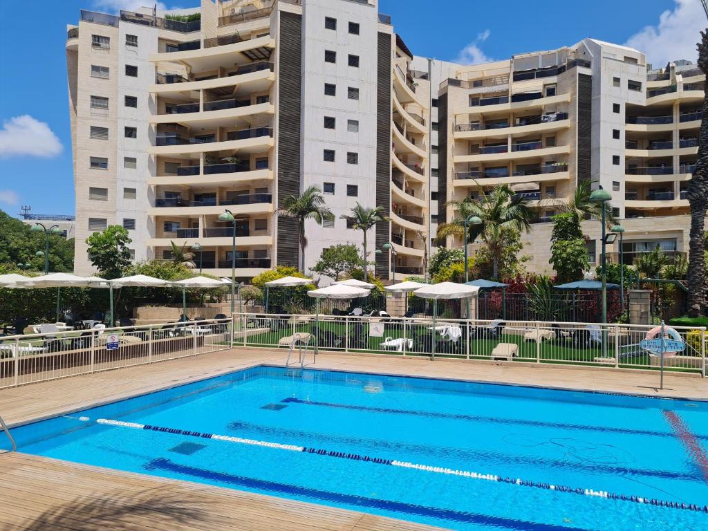 a swimming pool in front of some apartment buildings at Amazing Apartment in Raanana & Swimming up to 4 guests pool and Jacuzzi in Ra‘ananna