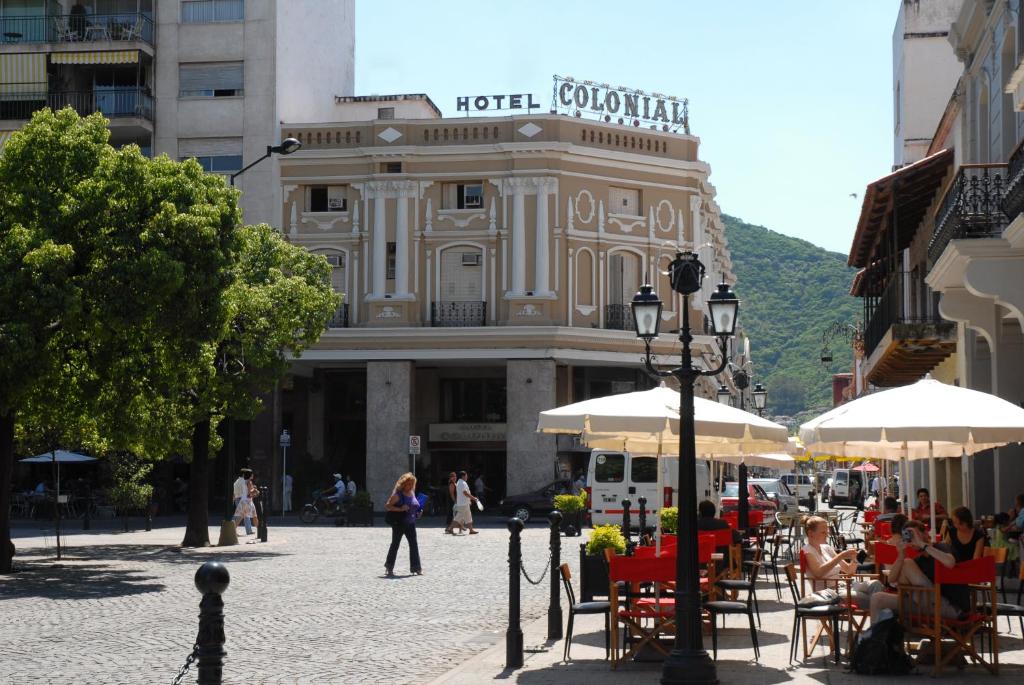 uma rua com mesas e guarda-sóis em frente a um edifício em Hotel Colonial Salta em Salta