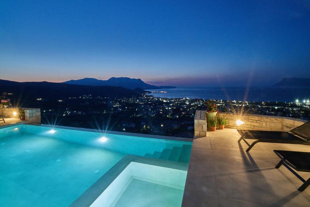 a swimming pool with a view of a city at night at Luxury Villa Argi infinity private pool in Kissamos