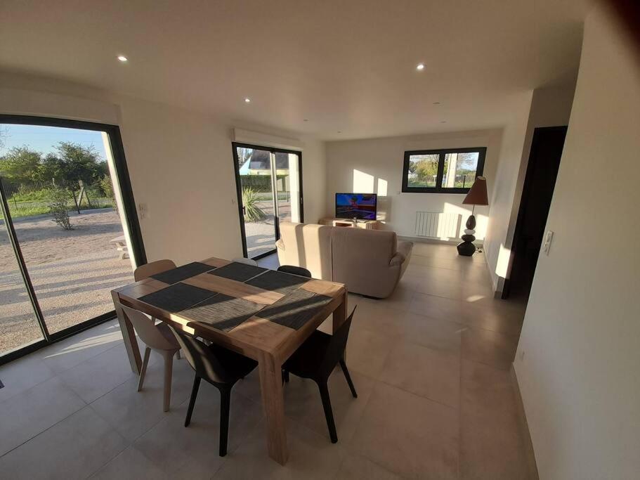 a dining room with a table and chairs and a living room at maison neuve a 1 km de la plage in Saint-Germain-sur-Ay