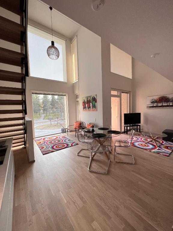 een woonkamer met een tafel en stoelen en een groot raam bij Three Monkeys Loft in Hyvinkää