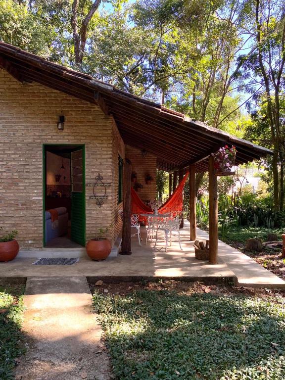 een bakstenen huis met een patio met een rood net bij Casa charmosa em condomínio arborizado in Nova Lima