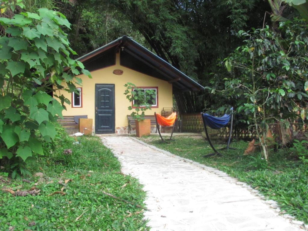 una pequeña casa amarilla con dos sillas delante en Nido de Pajaros, en Portachuelo