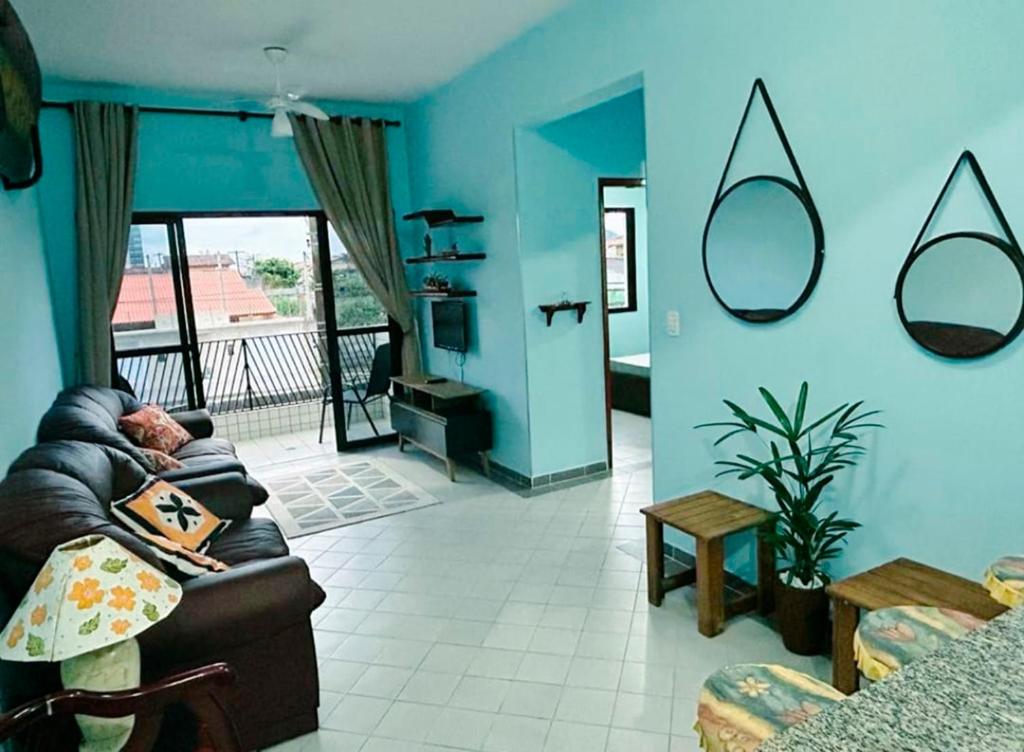 uma sala de estar com paredes azuis e um sofá em Ap beira-mar com wi-fi e garagem em Mongaguá